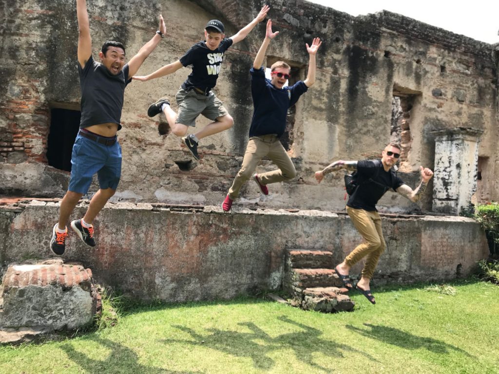4 young adults jumping in front of a Guatemalan building
