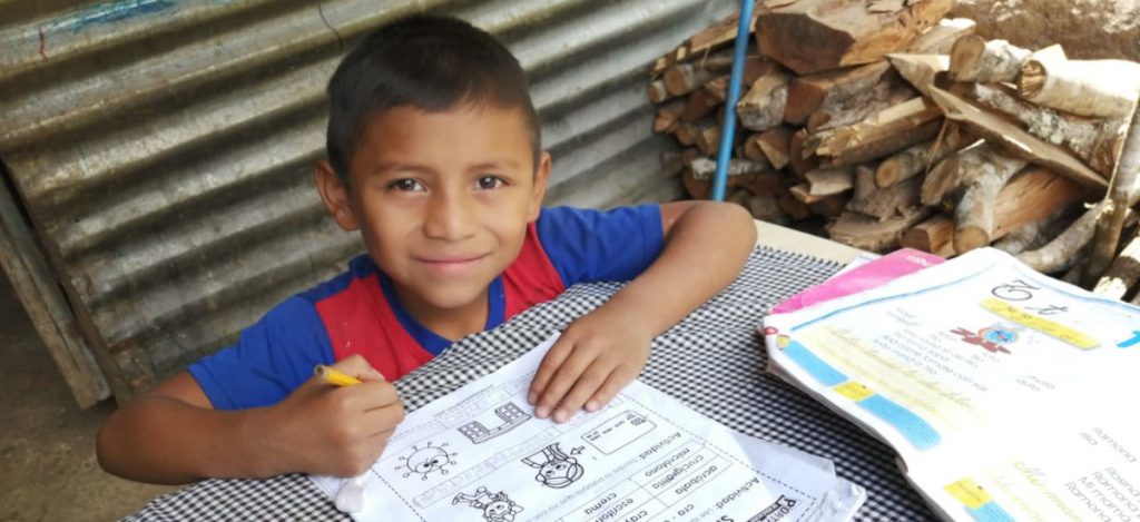 Axel working on schoolwork outside beside woodpile